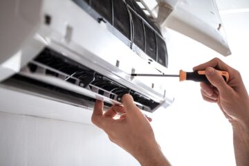 A person diligently repairing an air conditioner. Expertly handling emergency ductless AC repair services.