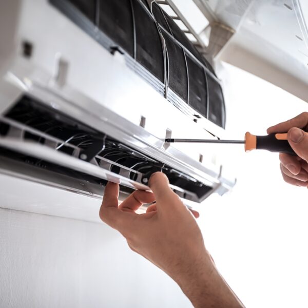 A person diligently repairing an air conditioner. Expertly handling emergency ductless AC repair services.