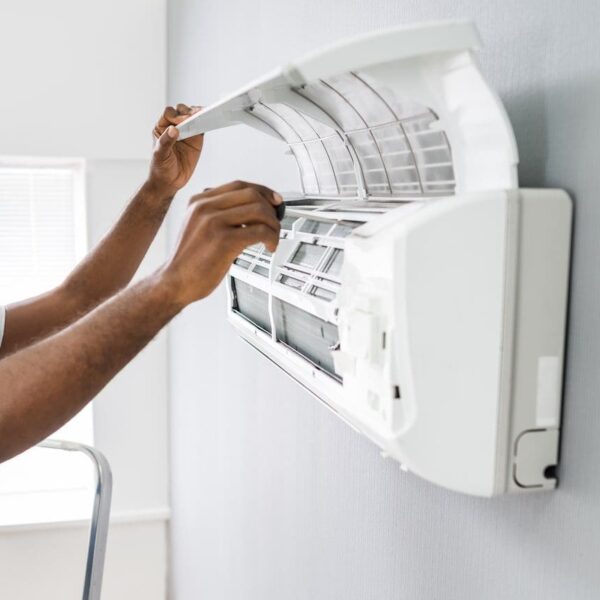 An expert in a hard hat and blue shirt diligently fixes an air conditioner. Our AC Repair in Lafayette ensures swift and effective cooling system fixes.